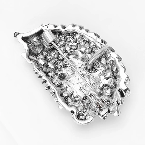 Macro detail of the silver alloy leaf brooch back showing secure pin closure mechanism