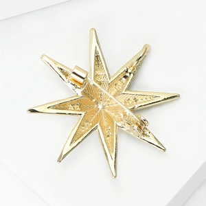 Detailed back view of the gold eight-point star brooch with safety pin and matte texture
