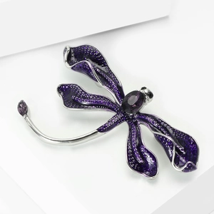 Macro view of purple enamel dragonfly brooch with faceted gemstone and fine glitter