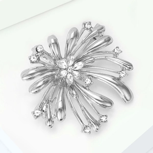 Détail d'une broche feu d'artifice argentée sertie de zircons sur fond blanc épuré