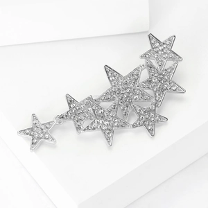 Detailed view of silver star brooch with radiant rhinestones on white geometric block
