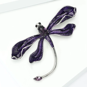 Macro shot of dragonfly brooch with purple enamel wings and polished silver alloy base