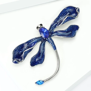 Detailed close-up of a blue dragonfly brooch with crystals and multifaceted gems