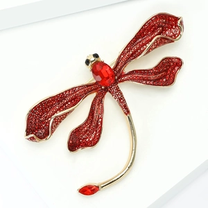 Macro detail of a dragonfly brooch with vibrant red crystals and a gold alloy base