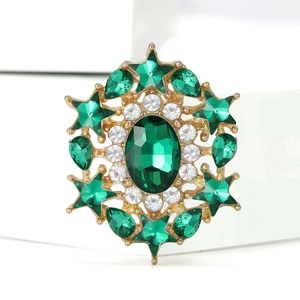 Macro shot of luxury gold brooch with green crystals and white zircon star pattern