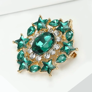 Macro shot of an emerald green oval crystal brooch with sparkling star-shaped rhinestones