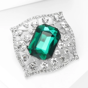 Macro detail of emerald cut green crystal brooch with silver pave rhinestone frame