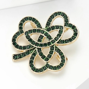 Détail d'une broche en forme de trèfle doré ornée de strass et de cristaux vert foncé