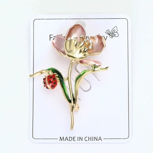Detail of enamel lotus brooch with pink petals, green leaves and a small ladybug