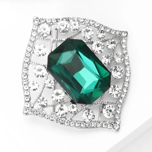 Detailed macro view of an emerald green glass brooch with crystal rhinestones on silver