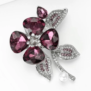 Dettaglio macro di elegante spilla a fiore con cristalli viola, gemme rosa e perla bianca