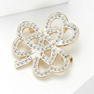 Détail de la broche trèfle dorée avec strass blancs et découpes en forme de cœur