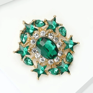 Macro shot of luxury emerald starburst brooch with gold plating and green gemstones
