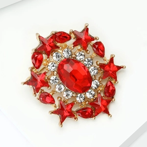 Close-up detail of a vintage gold alloy brooch with red oval crystal and white diamonds