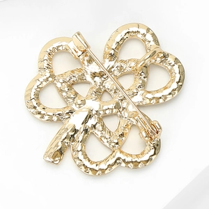 Détail de l'arrière d'une broche trèfle dorée avec fermoir de sécurité et boucle pendentif