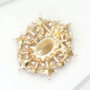 Detailed back view of a gold-plated alloy brooch with safety pin clasp and textured finish