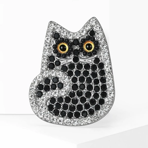 Sparkling crystal-encrusted cat brooch with amber eyes on a white minimalist display