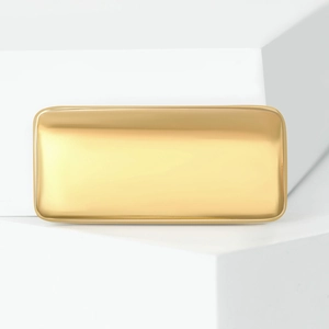 Macro shot of polished gold-tone liquid rectangular brooch on white geometric display stand