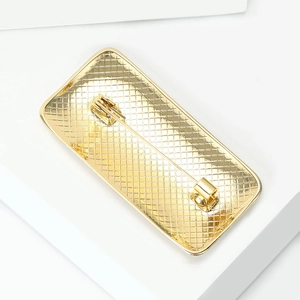 Macro detail of golden rectangular brooch back with grid texture and sturdy pin fastener