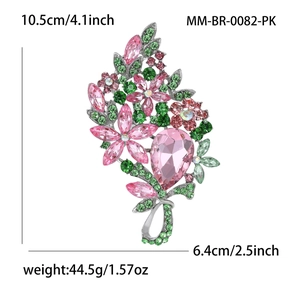Vintage crystal flower brooch with large pink drop stone and green leaves in silver setting