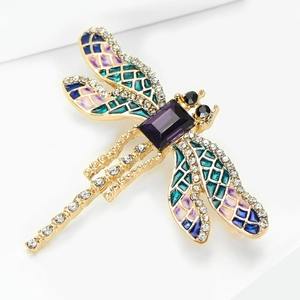 Dettaglio di una spilla a libellula con ali colorate, strass e gemma viola centrale