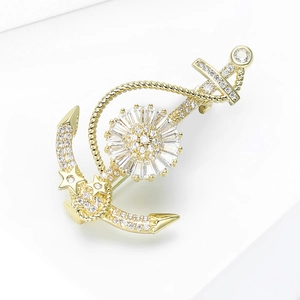 Détail d'une broche ancre avec motif tournesol, cristaux et étoiles dorées sur blanc
