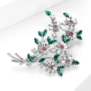 Détail d'une broche florale avec des cristaux roses et des feuilles en émail vert vif