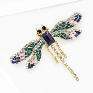 Dettaglio macro di spilla a libellula in smalto con cristallo viola e strass