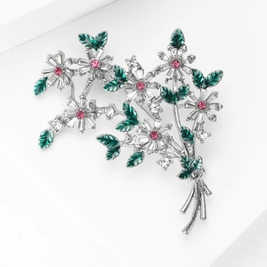Détail de la broche fleurie avec pétales en cristal blanc, centres roses et feuilles d'émail