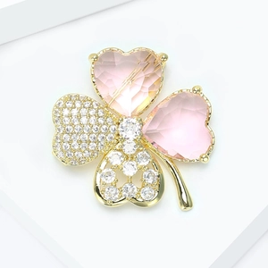 Détail de la broche trèfle dorée avec pierres de coeur roses et pavé de cristaux