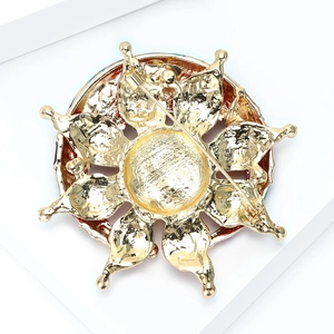 Detail view of the gold sunburst brooch back showing secure safety pin and texture