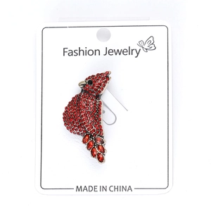 Detailed macro view of red rhinestone bird brooch showing sparkling gems on display card