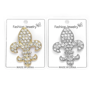Détail des broches fleur de lys en or et argent avec des cristaux de strass étincelants