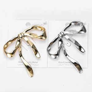 Polished gold and silver bow brooches made of eco-friendly metal on display card