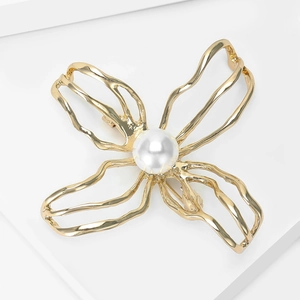 Detail view of a golden camellia brooch with a large white pearl on a display stand