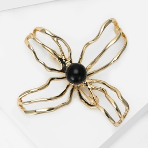 Detailed macro view of an elegant hollow golden camellia brooch with a black bead center