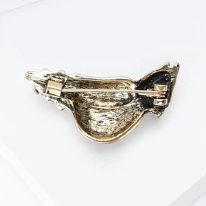 Detail view of the golden alloy back with textured finish and secure pin clasp on the brooch