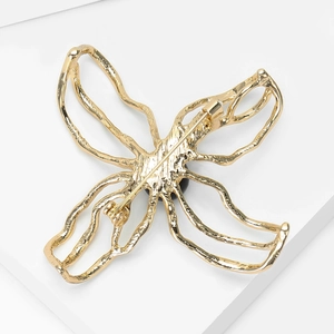 Detail view of the back of a gold butterfly brooch showing the secure pin clasp mechanism