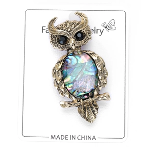 Close-up of vintage owl brooch with iridescent abalone shell and rhinestone eyes