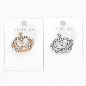 Détail de la broche couronne sertie de strass blancs en finitions or rose et argent