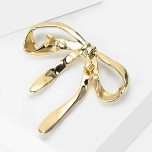 Macro shot of gold bow brooch back side showing the pin fastener mechanism details