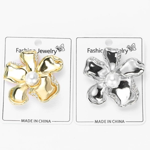 Close-up of golden and silver flower brooches with central pearls and small diamonds