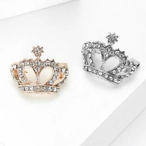 Élégantes broches couronnes dorées et argentées avec strass sur un socle blanc