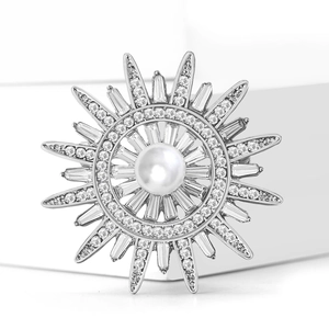 Broche soleil élégante avec perle blanche centrale et strass radiants sur un support