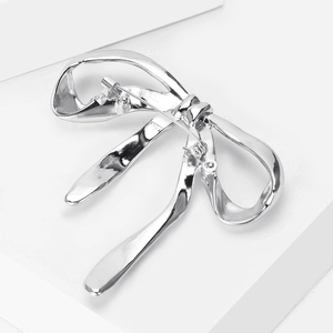 Detail view of silver ribbon bow brooch with liquid metal texture and secure back pin
