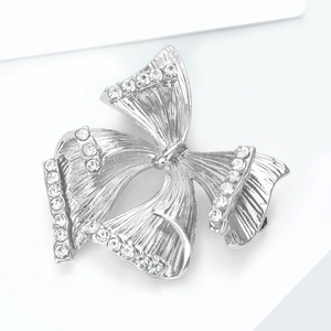 Détail de la broche nœud argentée avec bords en strass et texture en métal brossé