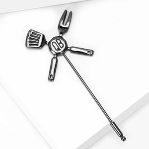 Detailed macro view of gunmetal kitchen utensil brooch featuring shovel and fork design