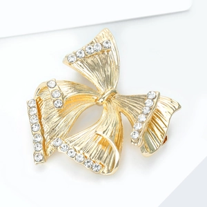 Détail macro d'une broche nœud dorée avec texture de soie et strass étincelants