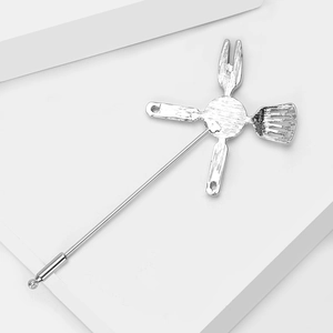 Detailed view of silver kitchen utensil brooch with brushed metallic texture finish