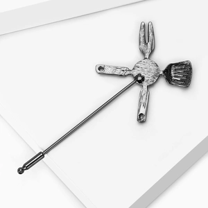 Detail of kitchen utensil brooch showing antique silver finish and brushed metal texture